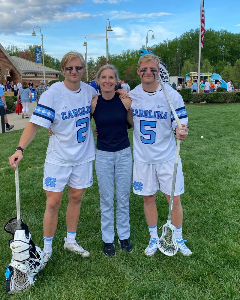 Henry, number 2, and Harrison, number 5, in their Carolina uniforms after a game, with their mom between them